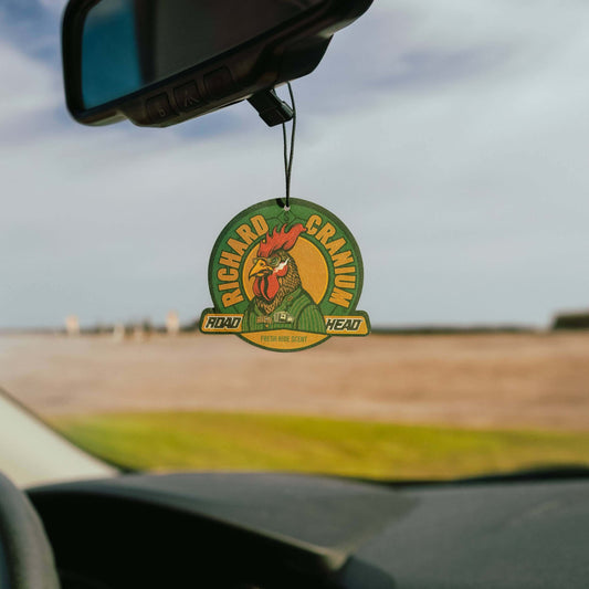 Car air freshener with rooster design hanging from rearview mirror.