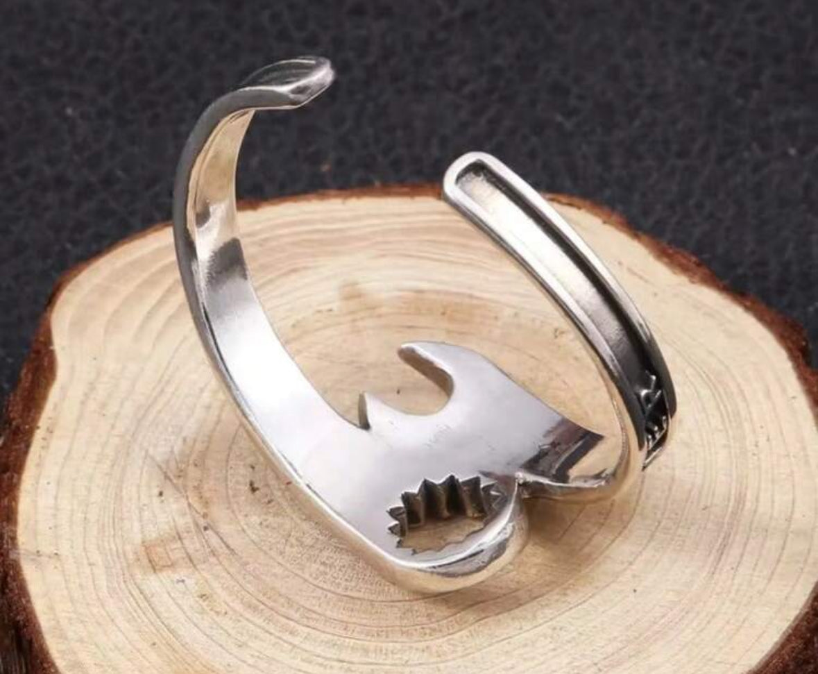 Silver bracelet with gear and bird design on wooden slice.