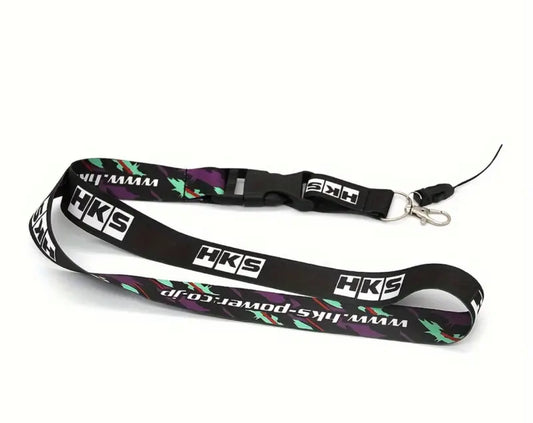 Black HKS lanyard with colorful leaf pattern and website text.