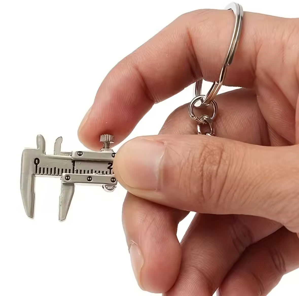 Hand holding a miniature metal caliper keychain.