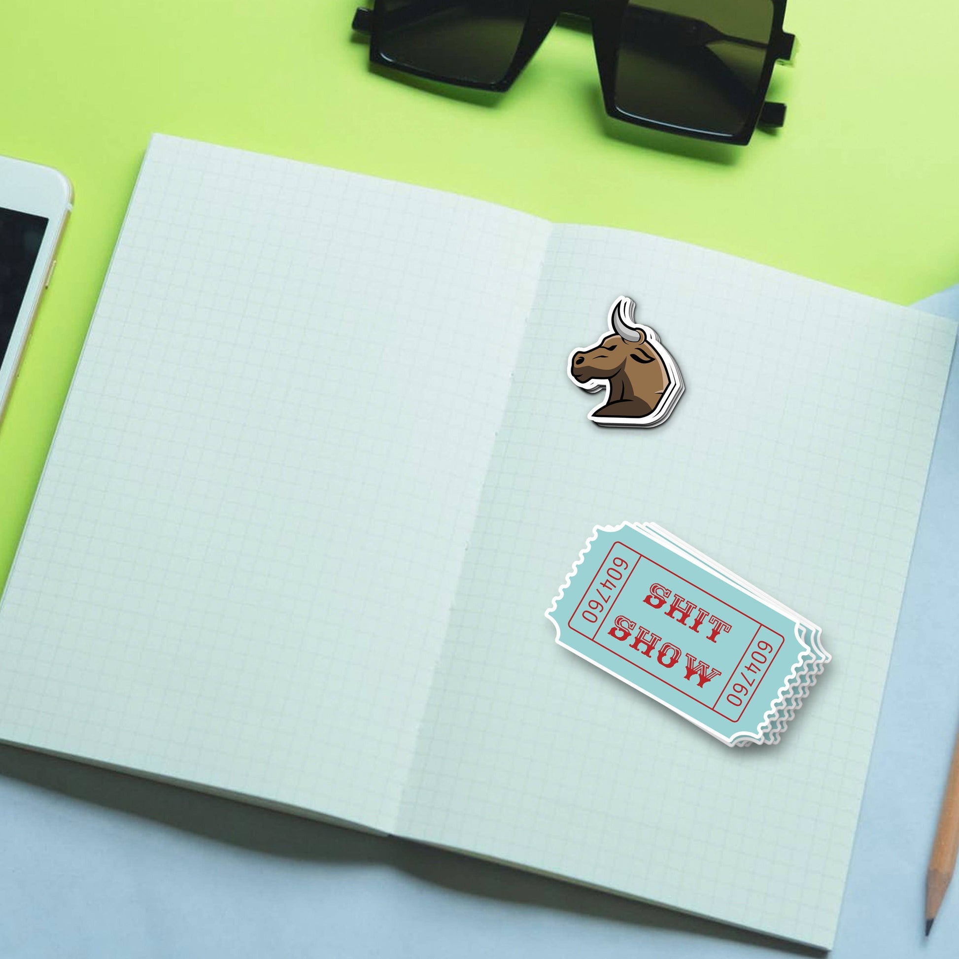 Sticker with bull head and SHIT SHOW ticket design on notebook.