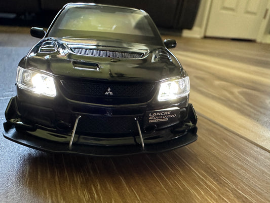 Black Mitsubishi Lancer Evolution model car on wooden floor.