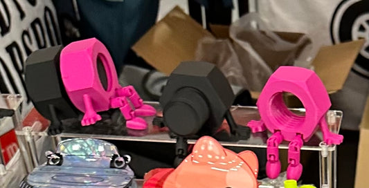 Pink and black 3D-printed nut and bolt toys on display.