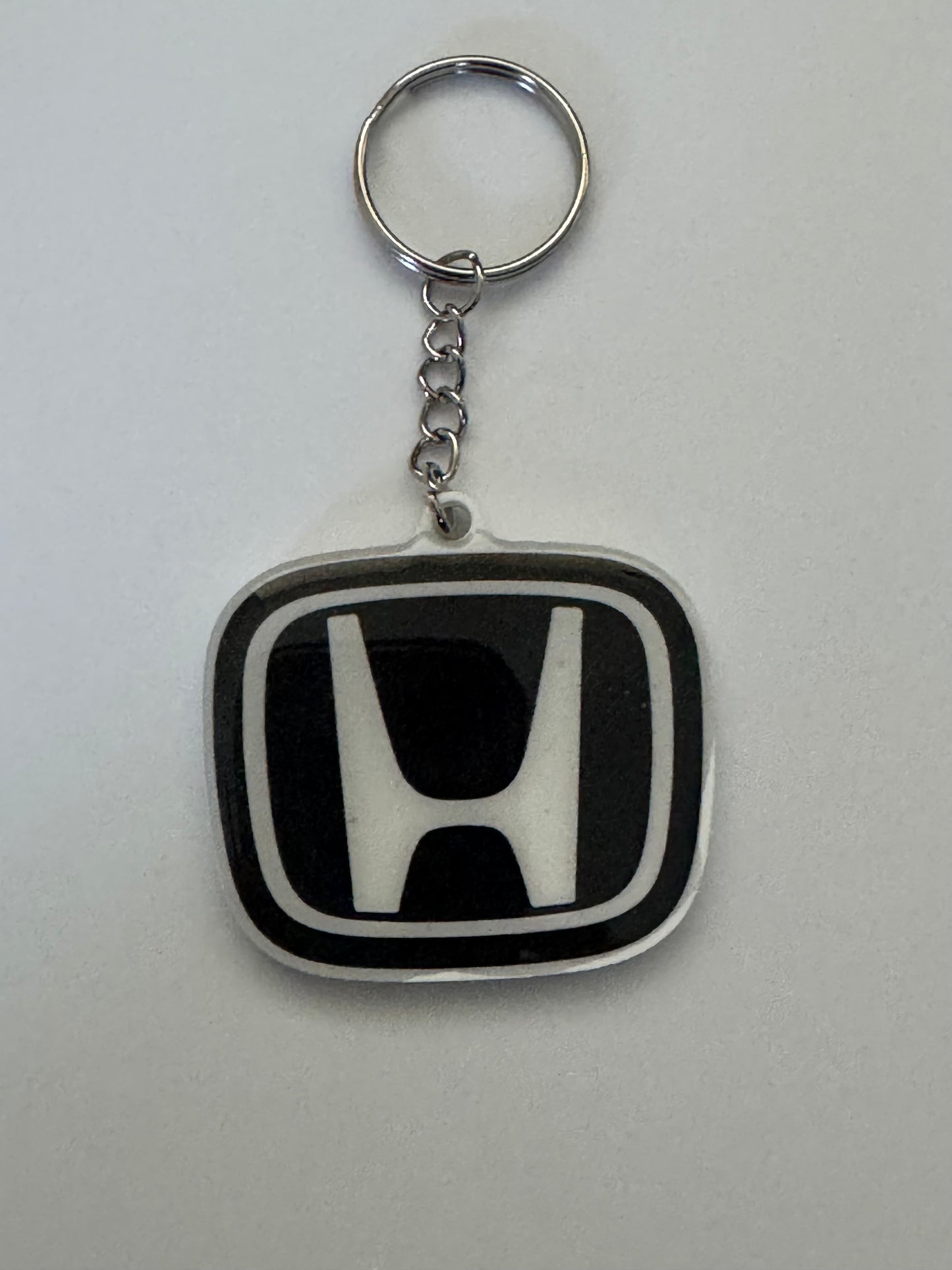 Honda logo keychain with silver ring and chain on a white background.