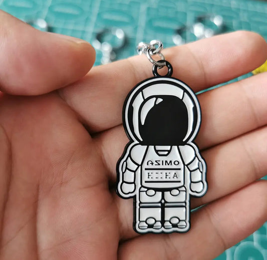 Astronaut keychain with ASIMO text, held in a hand.