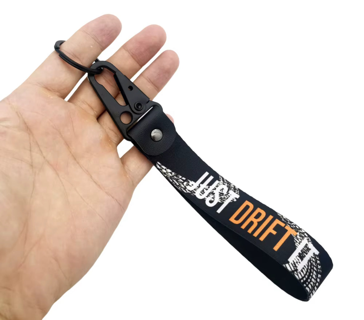Black keychain with JUST DRIFT text and tire tread design, held in hand.