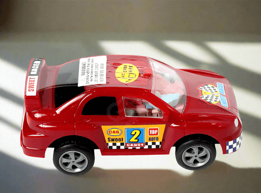 Red toy race car with stickers and driver figure inside.
