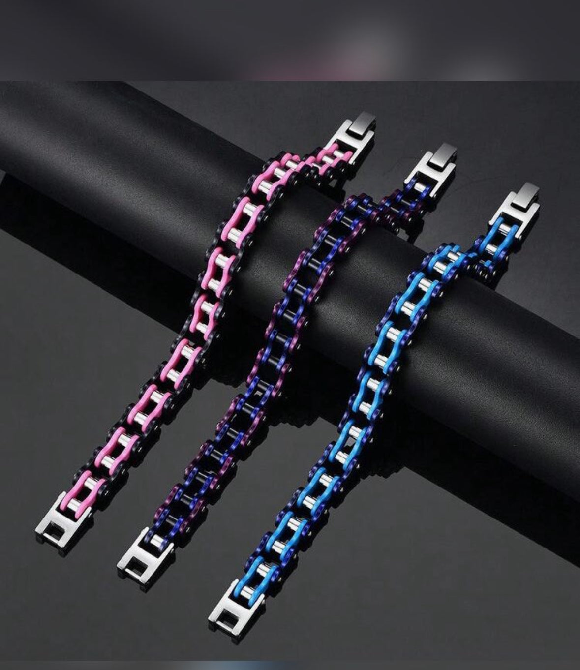Colorful chain link bracelets with metallic clasps on a black surface.
