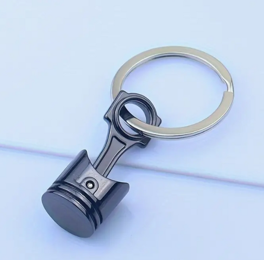 Black piston-shaped keychain with silver ring.