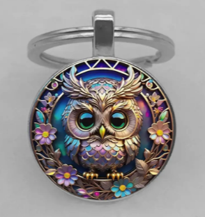 Colorful owl design on a round keychain with floral accents.