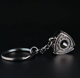 Silver car emblem keychain with black background.