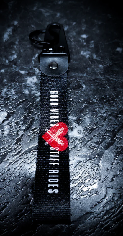 Black keychain with GOOD VIBES STIFF RIDES and red heart design.