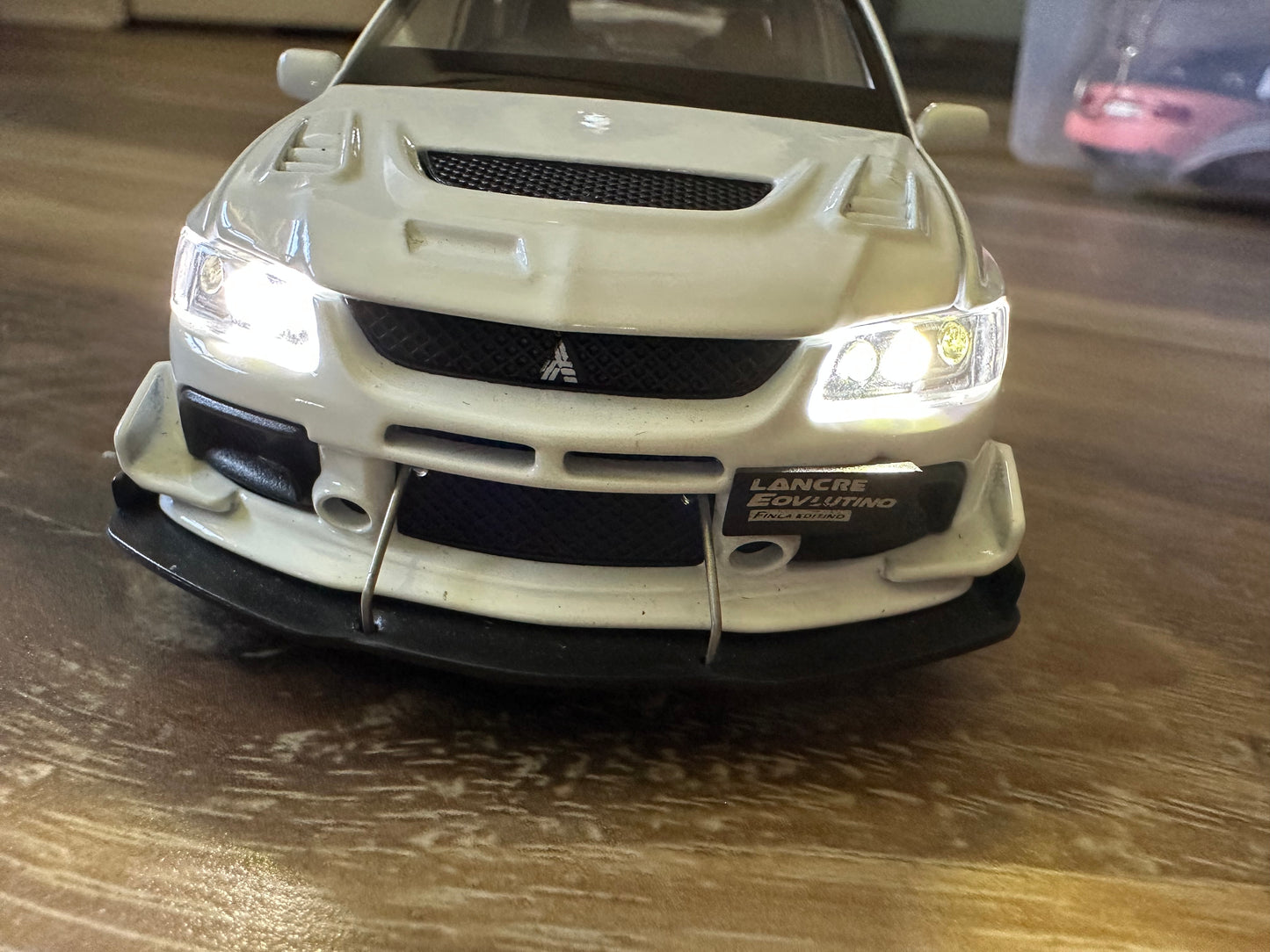 White Mitsubishi Lancer Evolution model car with front bumper and headlights.