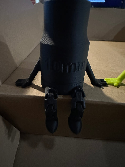 Black 3D-printed rocket model with 10mm text, standing on cardboard.