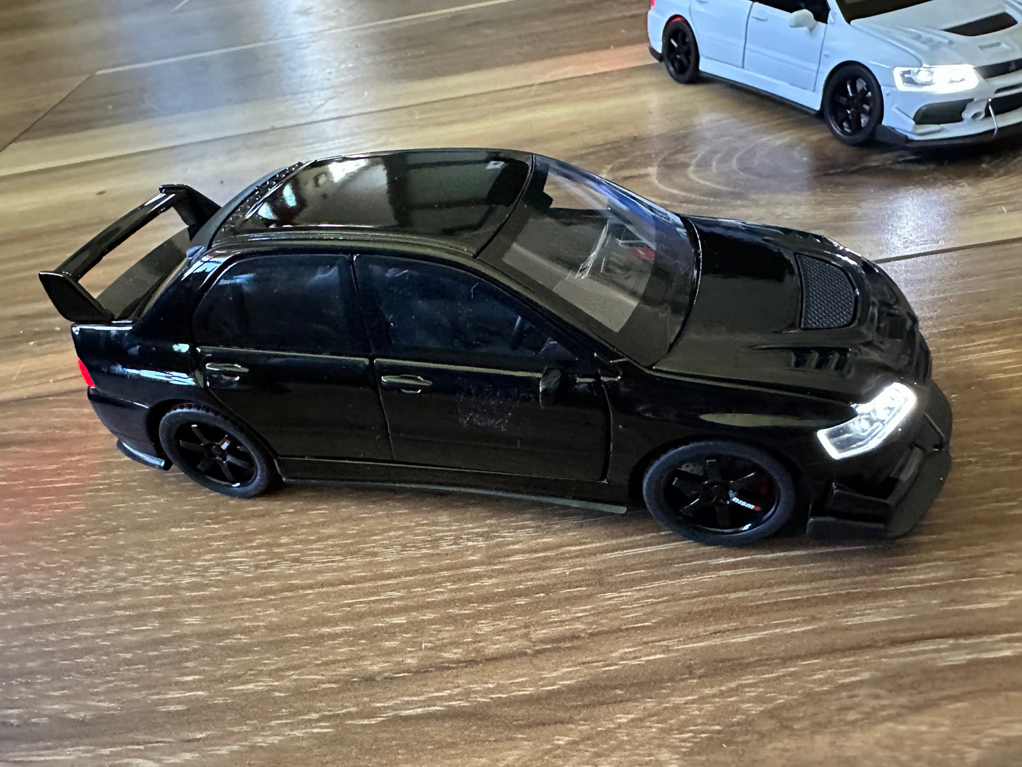 Black toy car with spoiler on wooden surface.