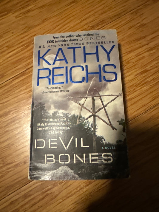 Kathy Reichs Devil Bones book cover with a pentagram on a wooden surface.