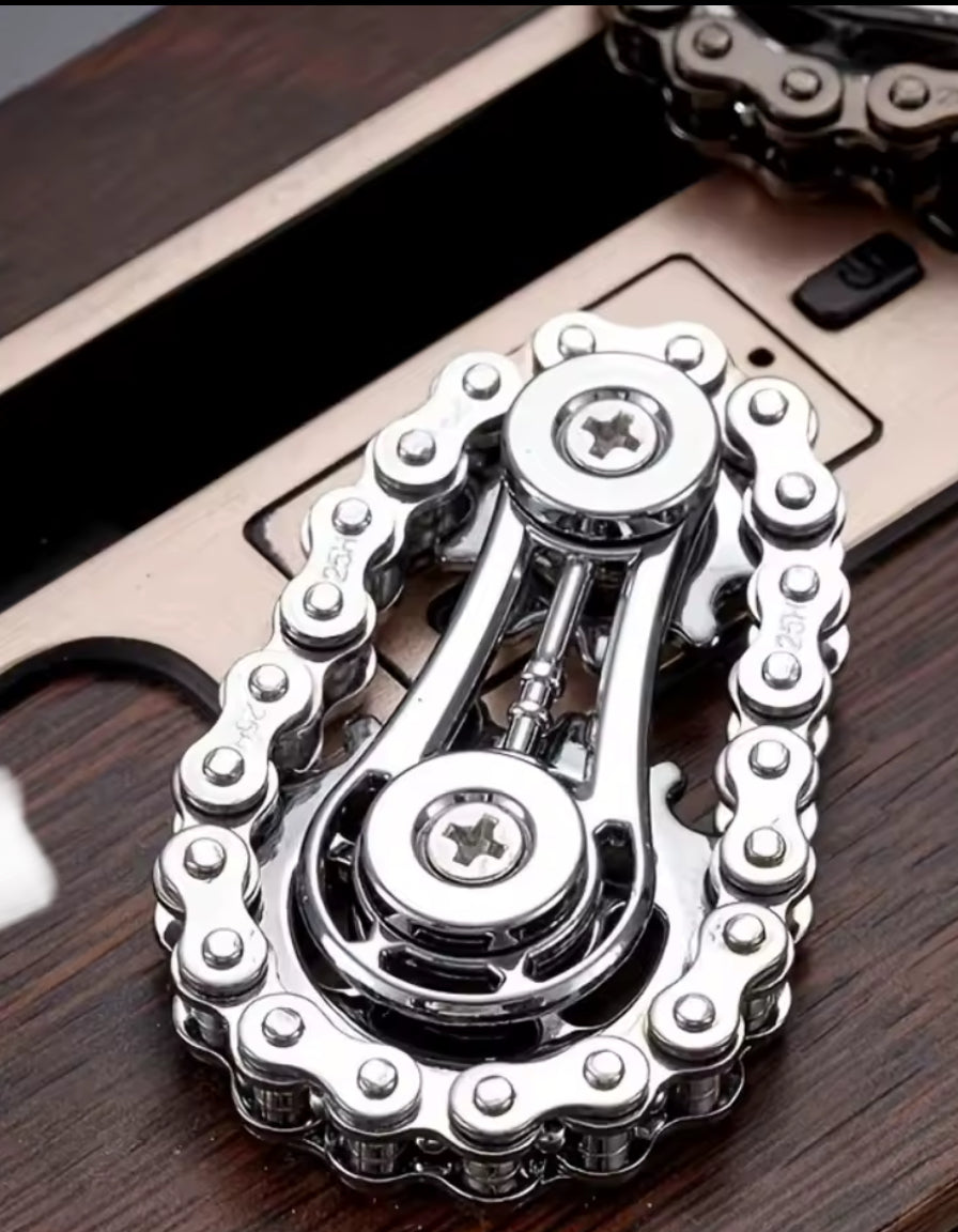 Chrome bicycle chain fidget spinner on wooden surface.