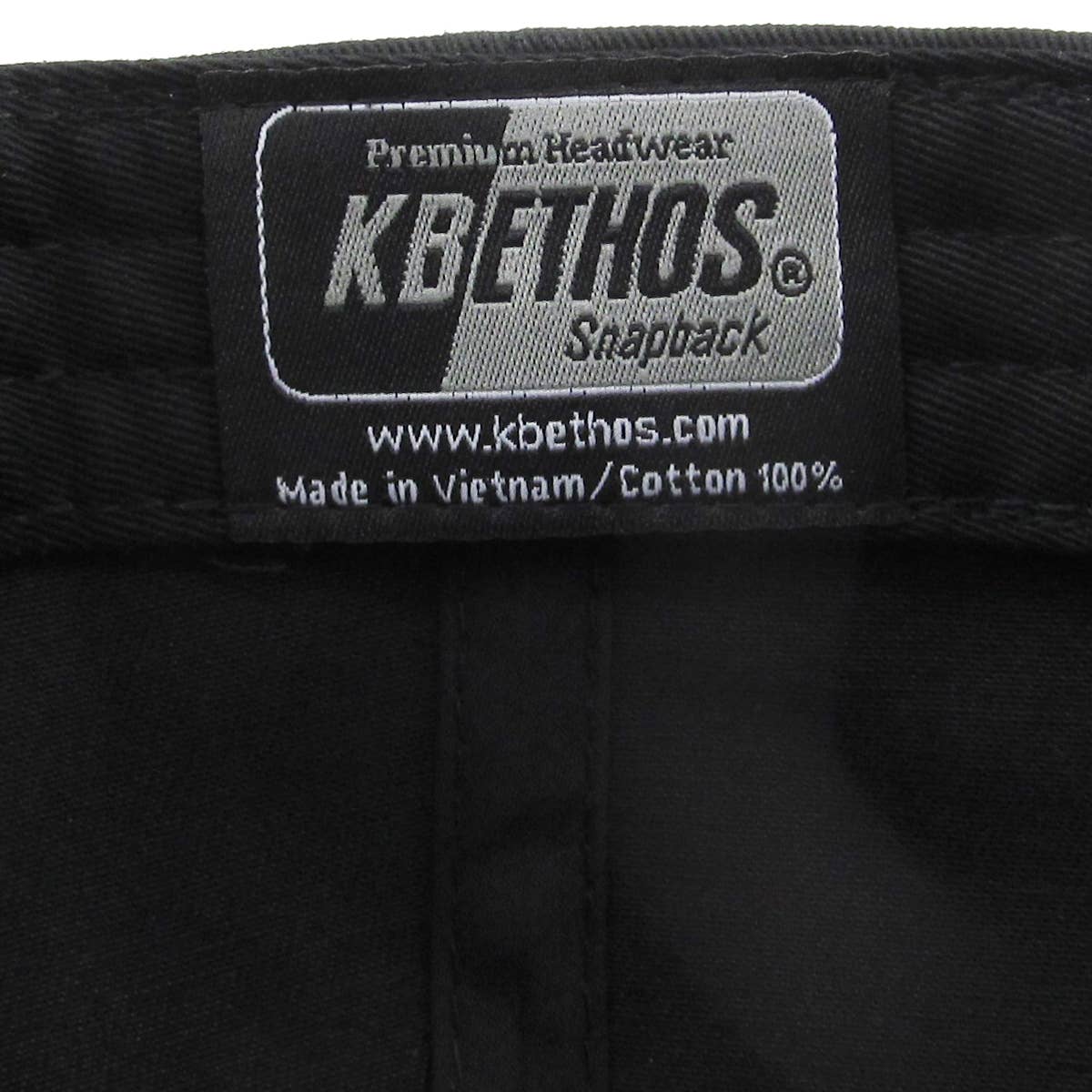 Black KBETHOS snapback hat label showing brand and details.