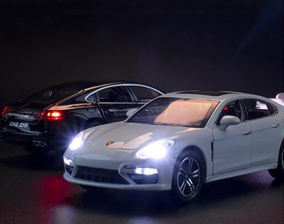 White Porsche Panamera model with illuminated headlights in a dark setting.