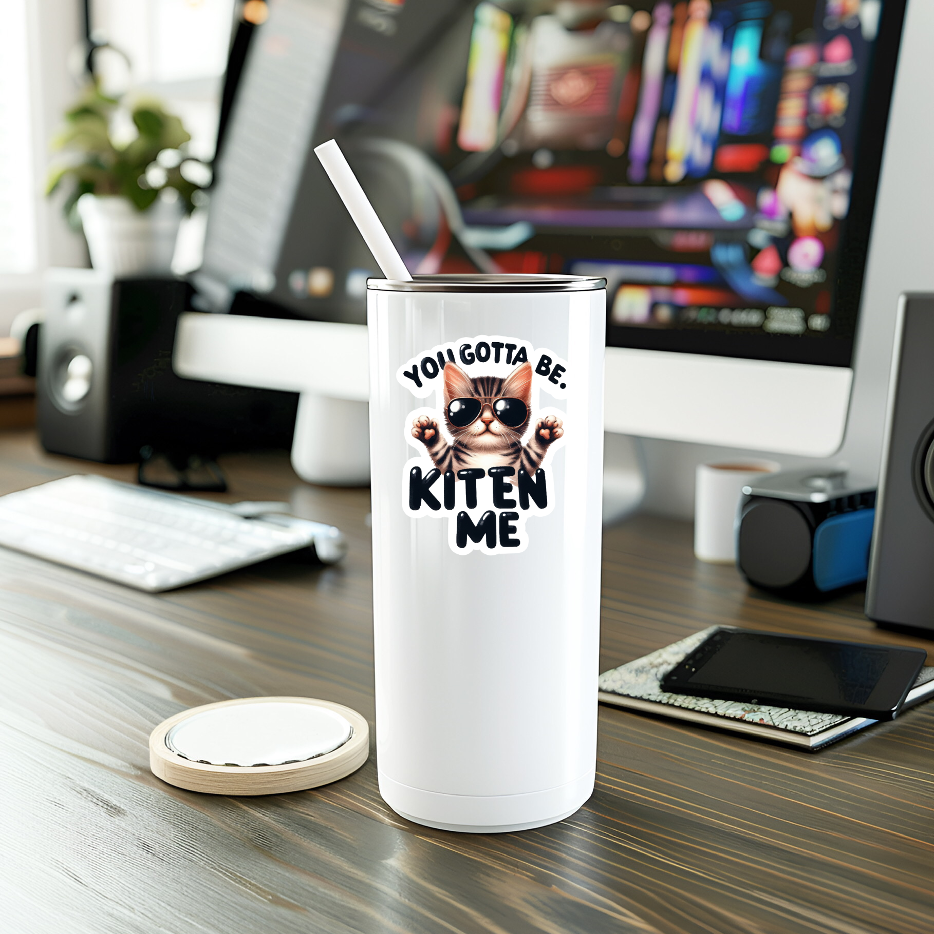 White tumbler with cat sticker reading YOU GOTTA BE KITEN ME on desk.