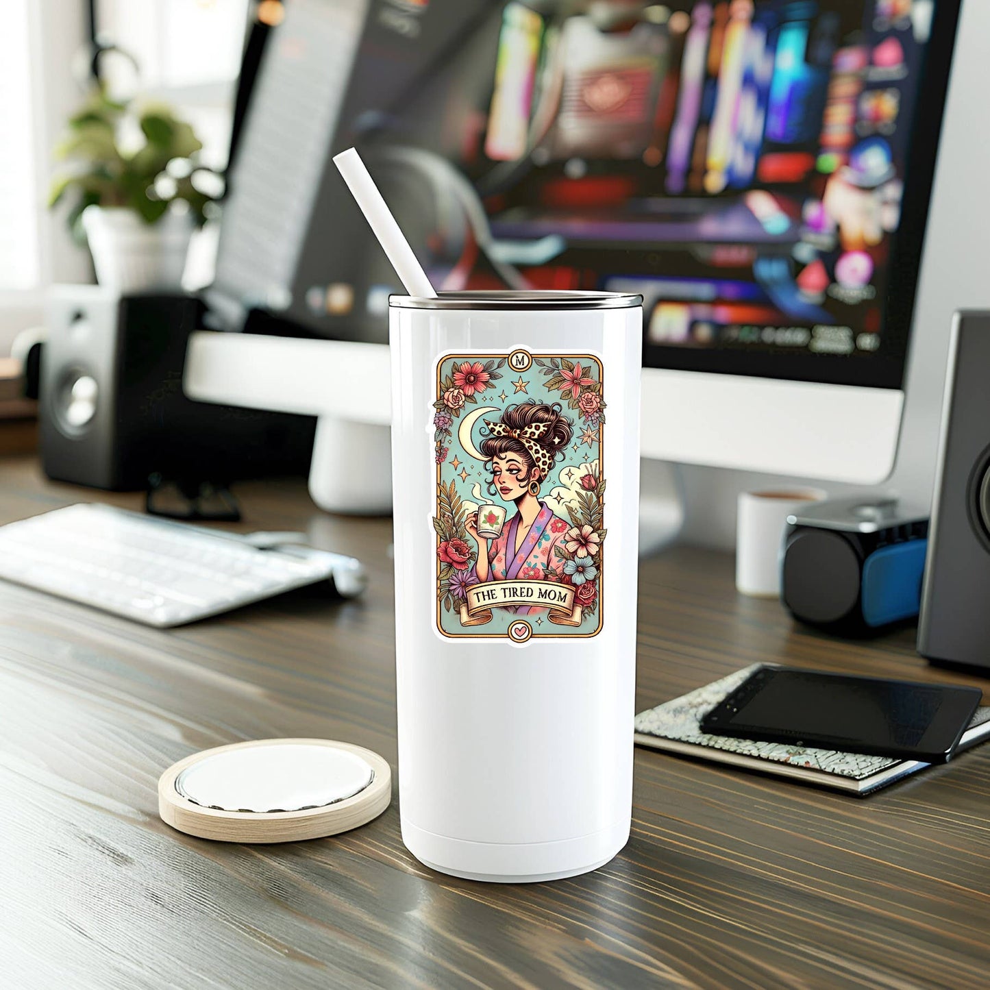 White tumbler with The Tired Mom design on desk.
