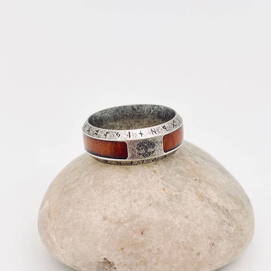 Silver ring with runes and wood inlay on a stone.